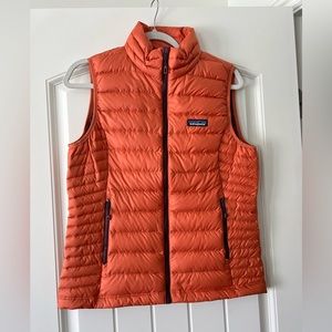 Women’s size M Patagonia goose-down vest Orange shell with purple inside lining.